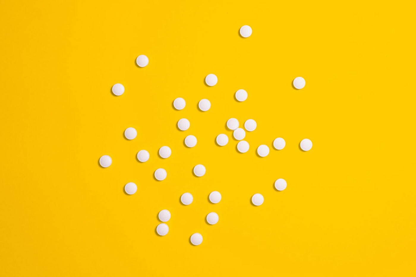 White tablets scattered on a yellow tray